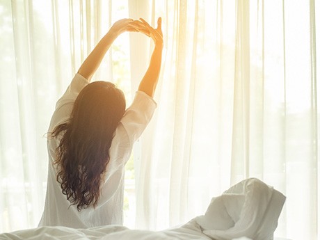 Woman sitting up in bed stretching