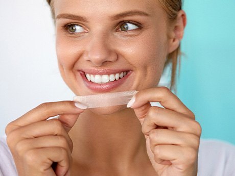 Woman about to apply whitening strip to upper arch
