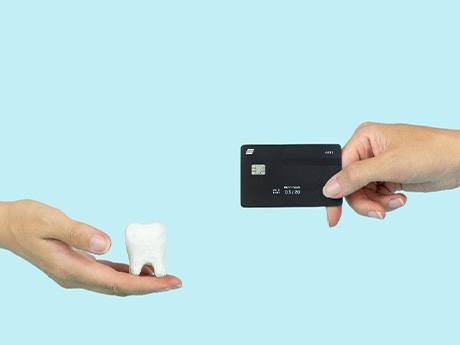 Hands holding out model tooth and black credit card