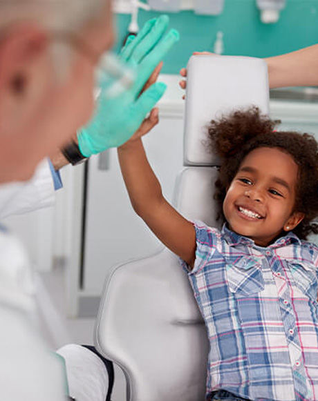 Smiling child giving dentist a high five