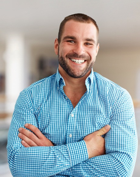 Man smiling at home with his arms folded