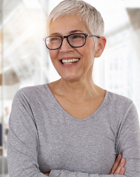 Senior woman with glasses smiling with arms folded