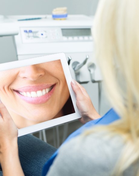 Woman looking at virtual smile design on tablet computer screen