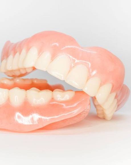 Upper and lower dentures arranged against neutral background