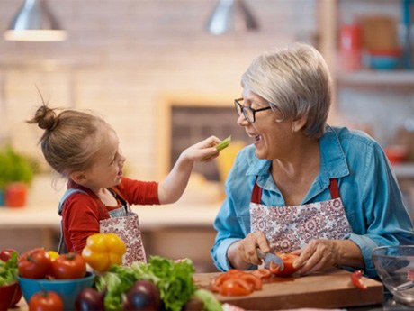a woman eating vegetables with her granddaughter 