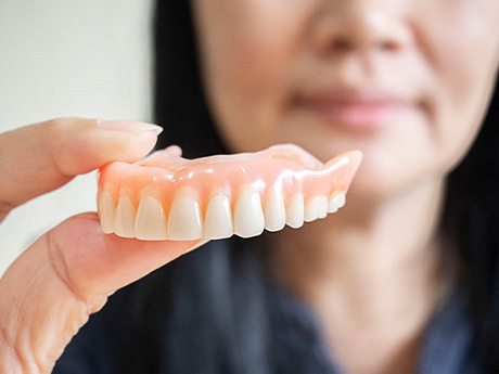 Woman holding a set of dentures