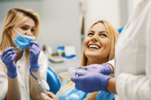 Woman laughing with friendly dentist and dental team member