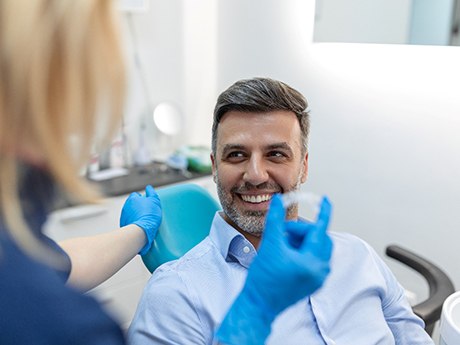 a dentist showing a patient how to use Invisalign trays