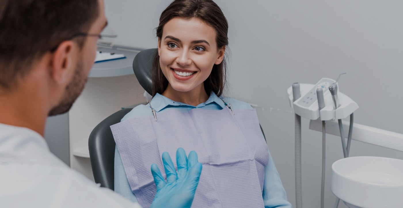Woman in dental chair smiling at dentist