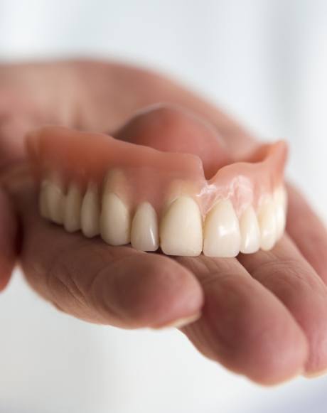 Hand holding full denture