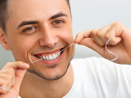 man flossing teeth in bathroom