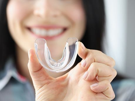 woman smiling while holding mouthguard
