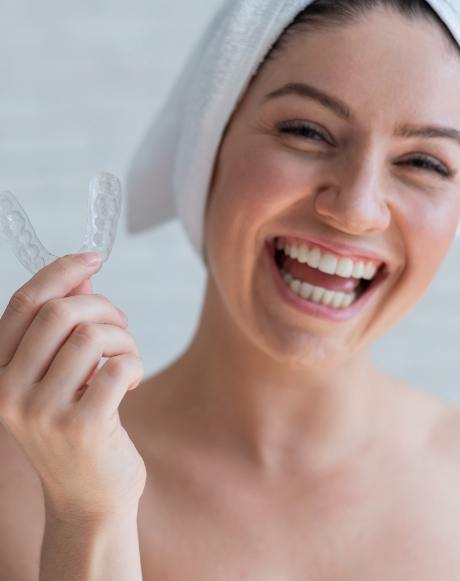 Smiling woman holding a nightguard for bruxism