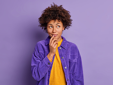 Woman with curly hair wondering in purple jacket