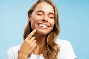 Woman smiling and pointing to her dental restoration