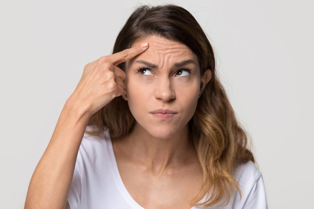 A woman looking at her forehead wrinkles